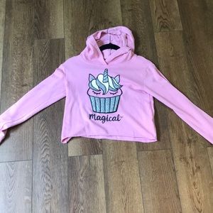 A pink cropped Justice hoodie with print on the front
